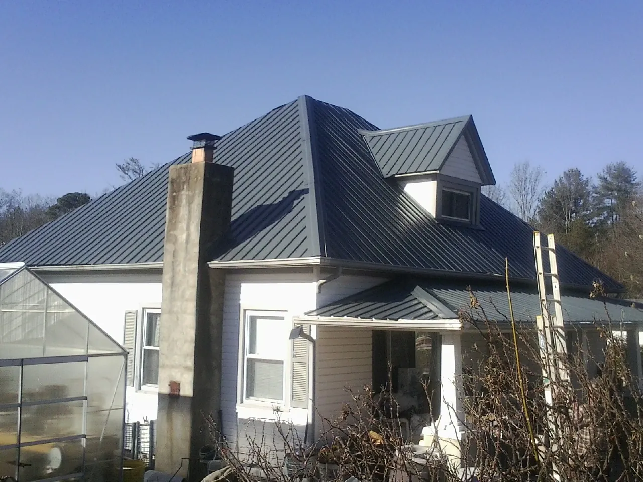 Dark blue standing seam metal roof on a white farmhouse with dormer — Slate & Tile Roof Repair by Roofing Brothers in Langley