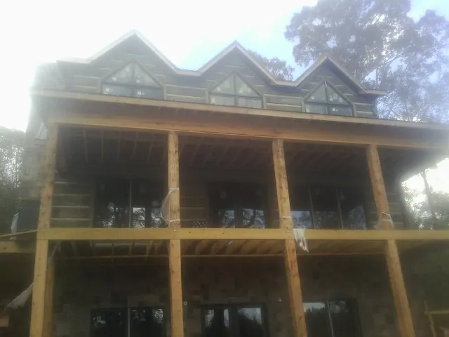 Dormers and porch framing on a large log home under construction — Roof Coating work by our crew in Langley