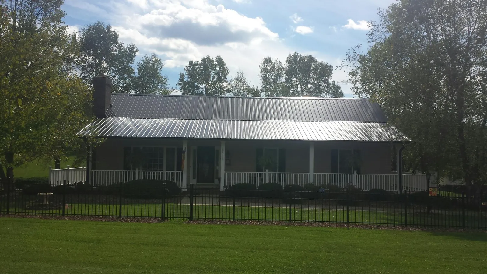 Gray metal roof on a brick ranch with a full width front porch — Gutter Guard Installation work by our crew in Langley