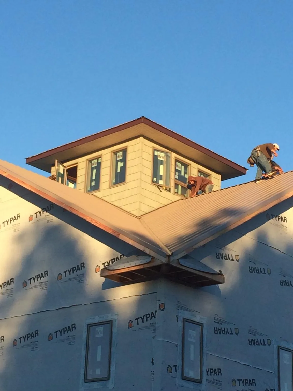 Roofers working around a rooftop cupola on a new metal roof at sunset — Roof Waterproofing in Langley by Roofing Brothers
